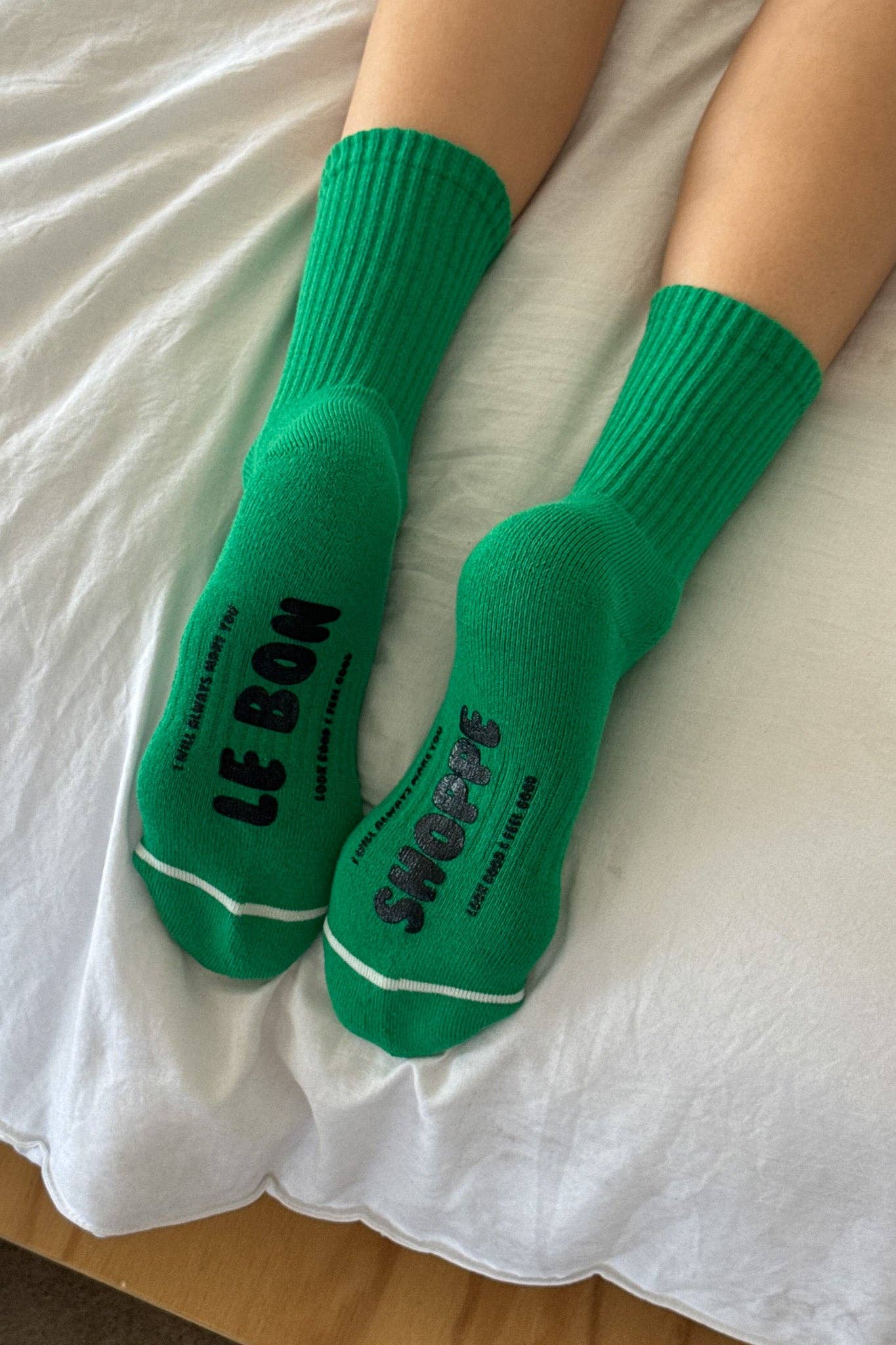 Green socks with text on a white bed sheet