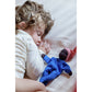 Child lying on a bed with a blue plush toy