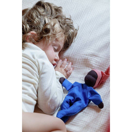 Child lying on a bed with a blue plush toy
