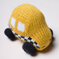 Knitted toy car in mustard yellow with black wheels on a light gray background