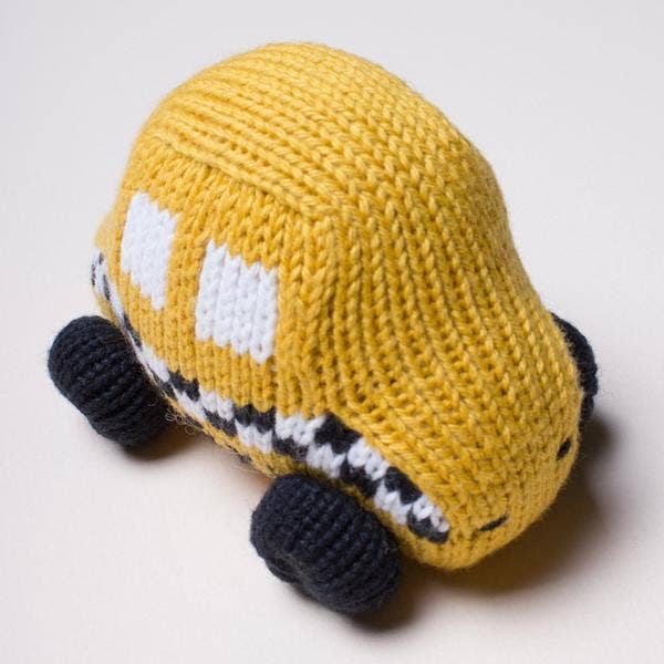 Knitted toy car in mustard yellow with black wheels on a light gray background