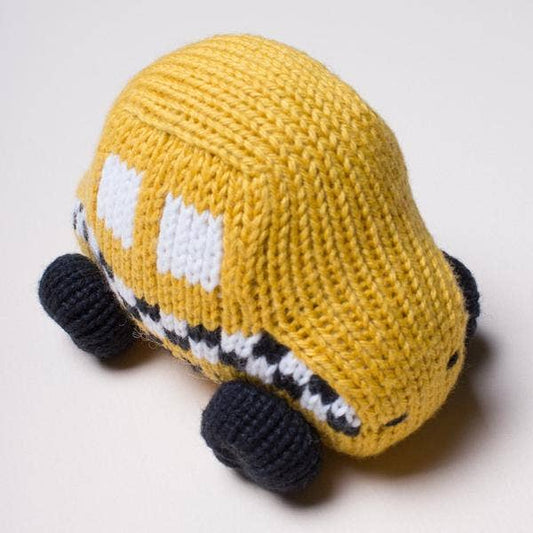 Knitted toy car in mustard yellow with black wheels on a light gray background