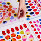 Colorful flower petal stickers with a hand interacting with them on a white background.