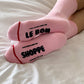Pink socks with text on a white bed