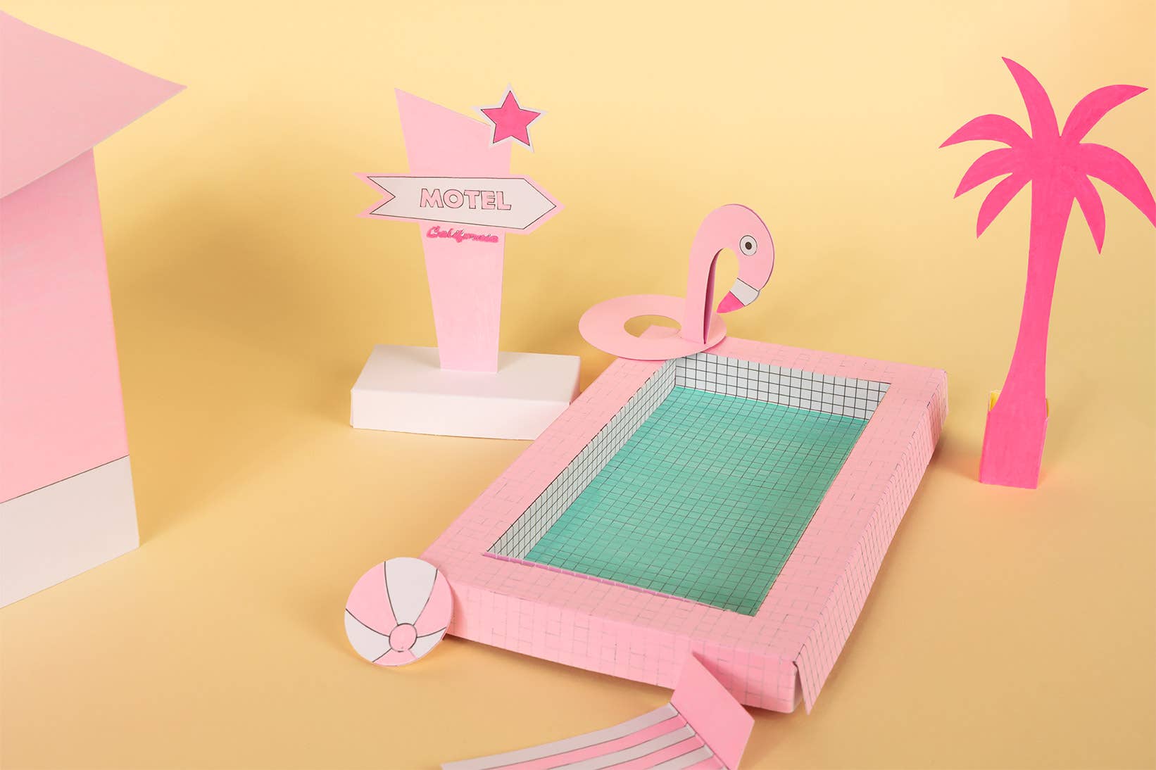 Pink flamingo-shaped cutting mat with palm trees and a motel sign on a yellow background