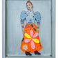 Colorful paper sculpture of a woman with a floral skirt in a gray frame