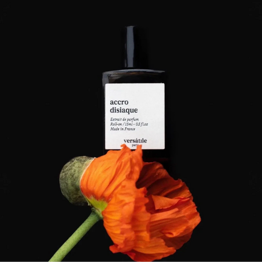 Perfume bottle labeled 'accro disique' with an orange flower on a black background