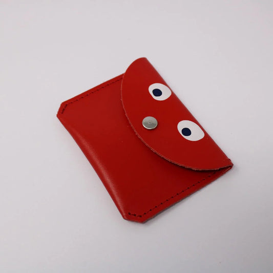 A rectangular ark colour design red googly eye purse. It has a silver button. The background is white. 