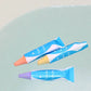 Two colorful crayon-like markers on a light blue surface