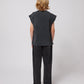 A back view of the model, showcasing the relaxed silhouette of the trousers with two patch pockets.