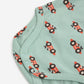 Green baby onesie with red tractor pattern on a white background