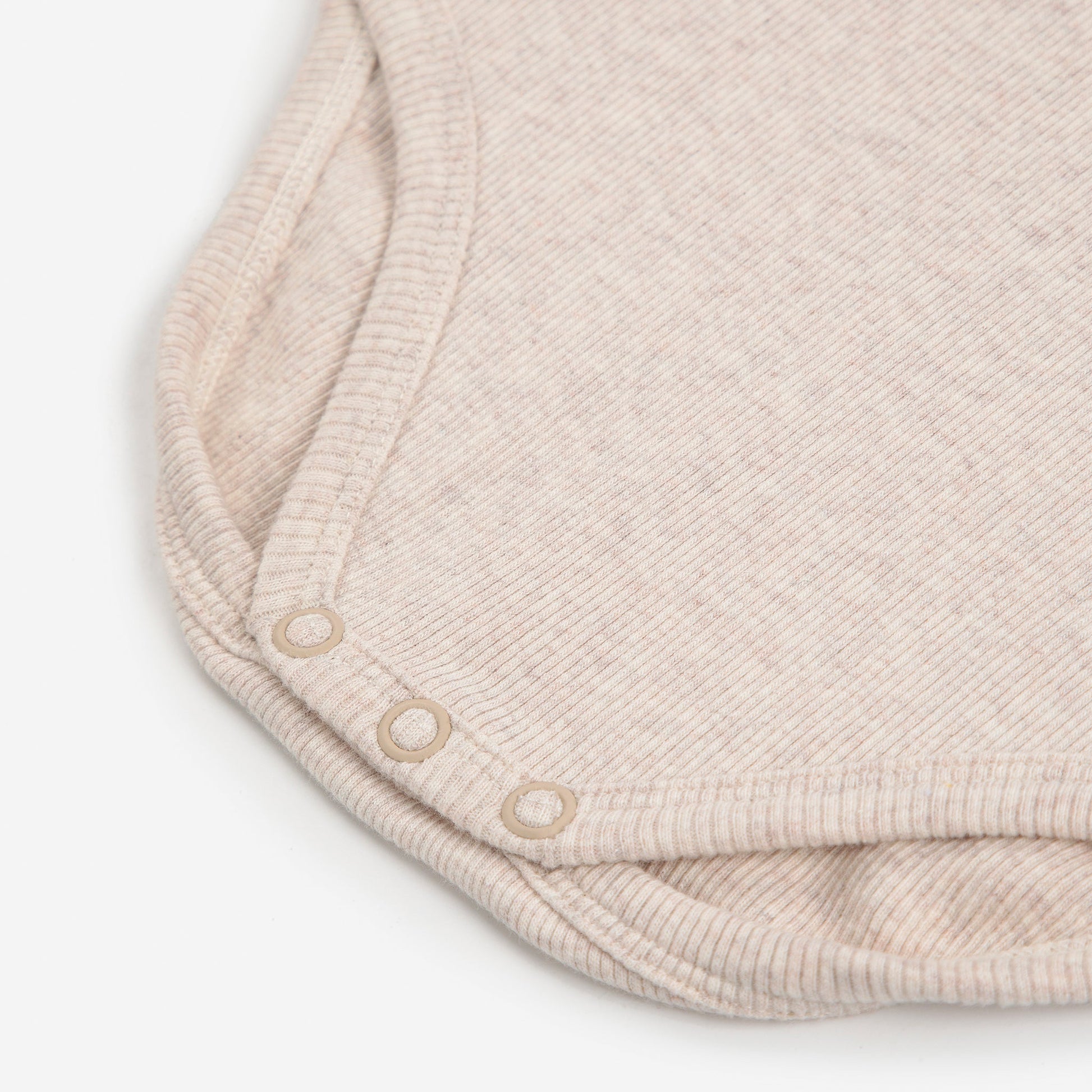 Close-up of a beige baby romper with buttons on a white background