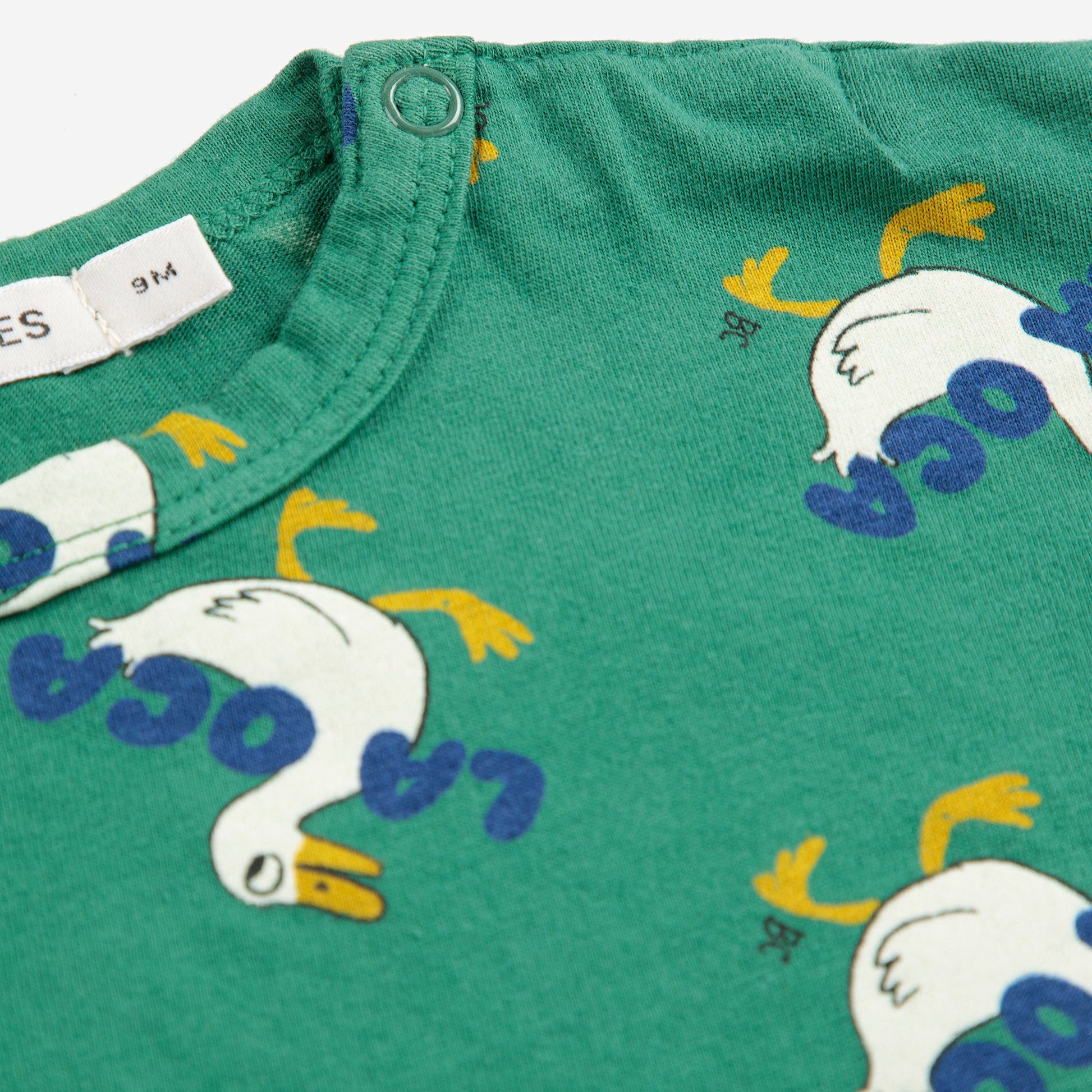 Green fabric with cartoon duck pattern and text on a white background