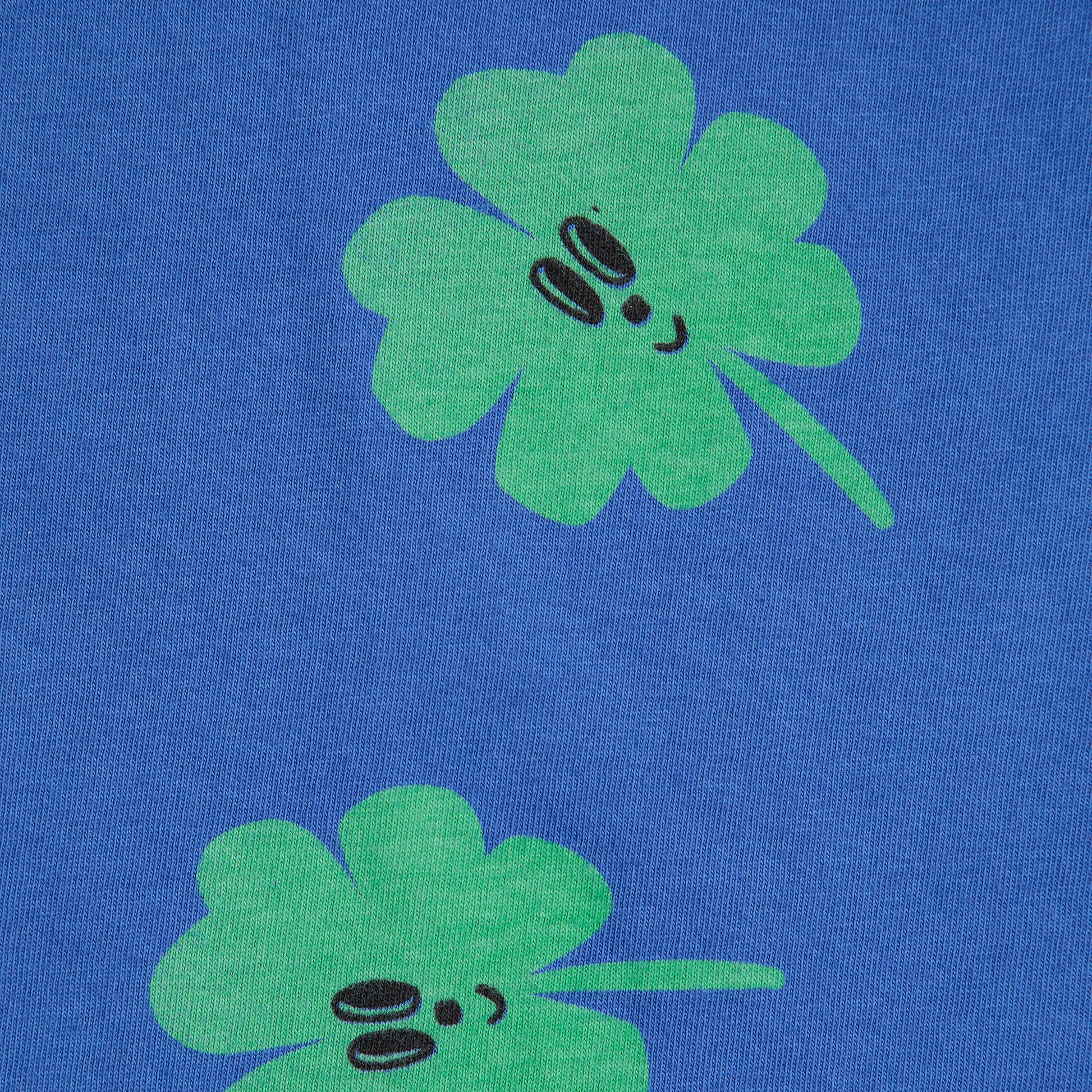 Two green four-leaf clover designs on a blue background