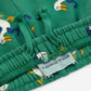 Green fabric with cartoon duck pattern and a visible label on a white background