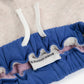 Close-up of blue baby romper with pink trim and 'Bogo Choses' label on a beige background