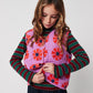 Young girl wearing a colorful quilted vest with a white background