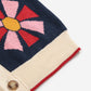 Close-up of a knitted garment with a colorful flower design on a white background