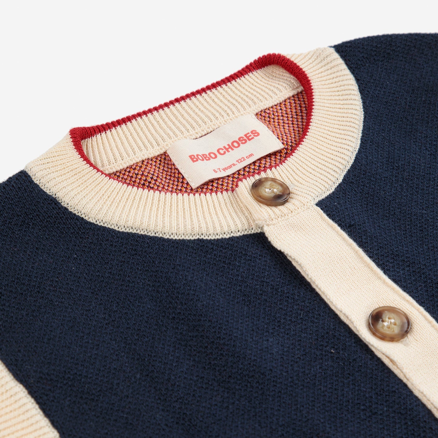 Navy sweater with white collar and red trim, featuring a brand tag.