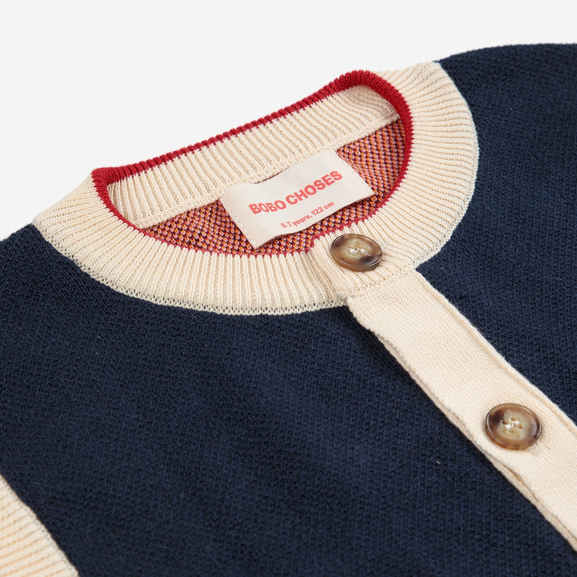 Navy sweater with white collar and red trim, featuring a brand tag.