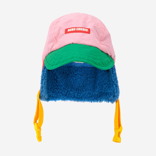 Colorful winter hat with pink top, green middle, blue bottom, and yellow ear flaps on a white background.