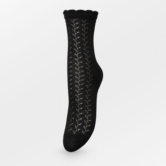 Becksöndergaard Leofa Cotta socks in black, featuring delicate transparent details, a wavy edge, and a subtle glittery finish, displayed elegantly against a neutral background.