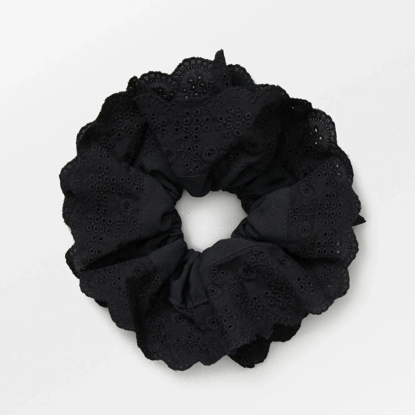 Becksöndergaard Black Musa Anglaise Scrunchie featuring a lace-like design, adding a delicate and feminine touch to hairstyles with its soft fabric and gathered elastic.