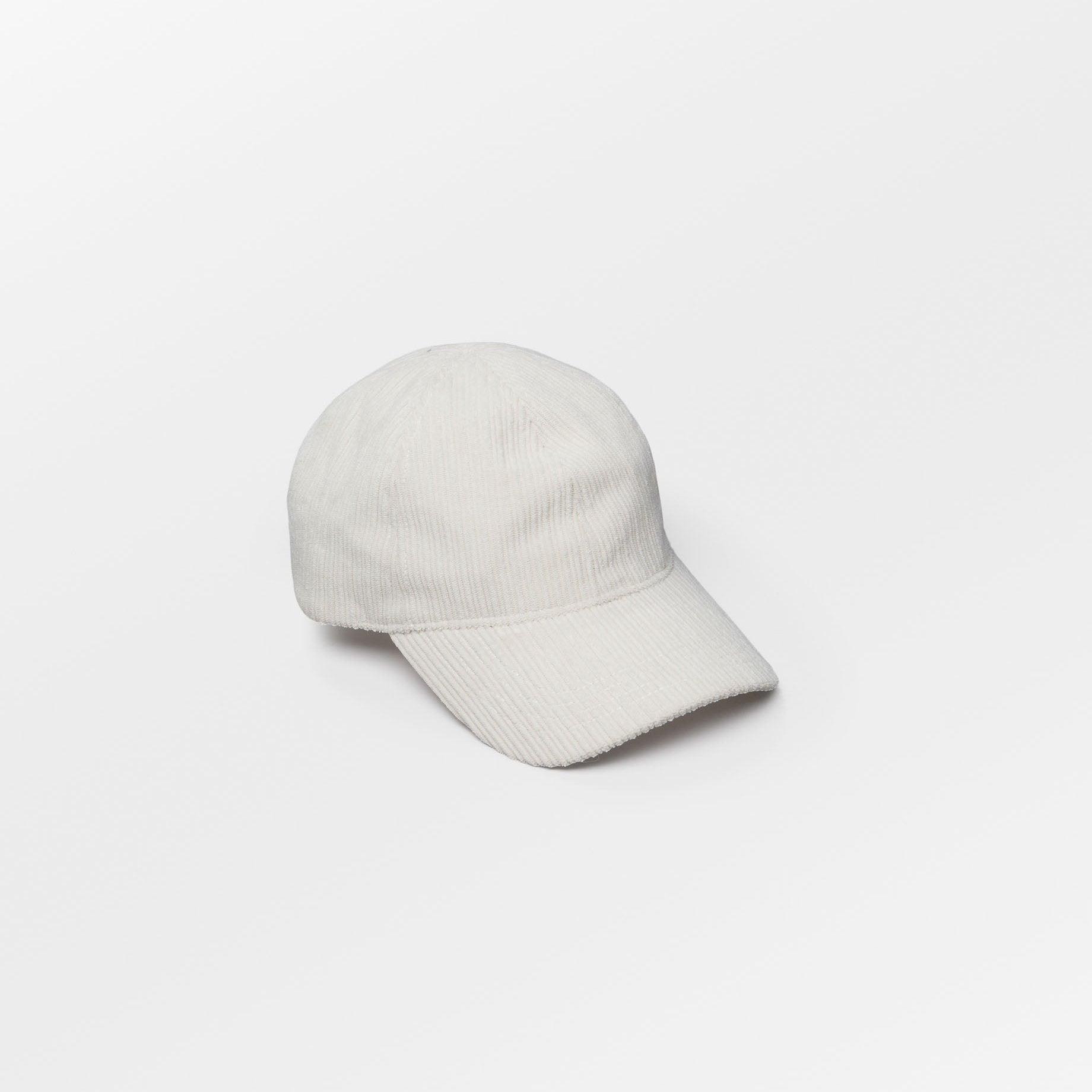 Becksöndergaard Malvi Cap in Off White, made from ribbed velvet corduroy, featuring an adjustable design and a discreet logo at the back. The cap is displayed on a neutral background, highlighting its stylish and unisex appeal.