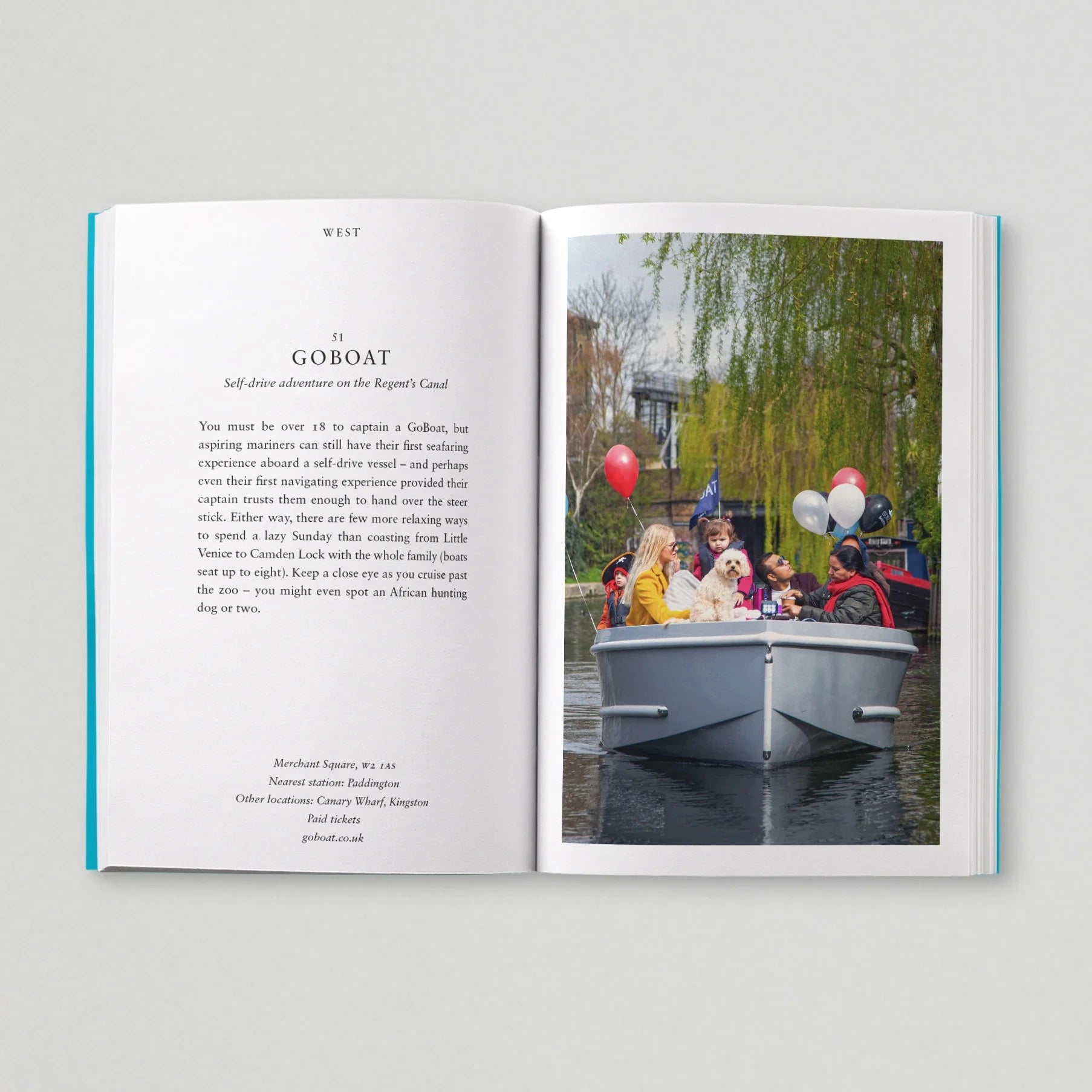 Open book with text on one page and a photograph of people on a boat on the other, against a light gray background.