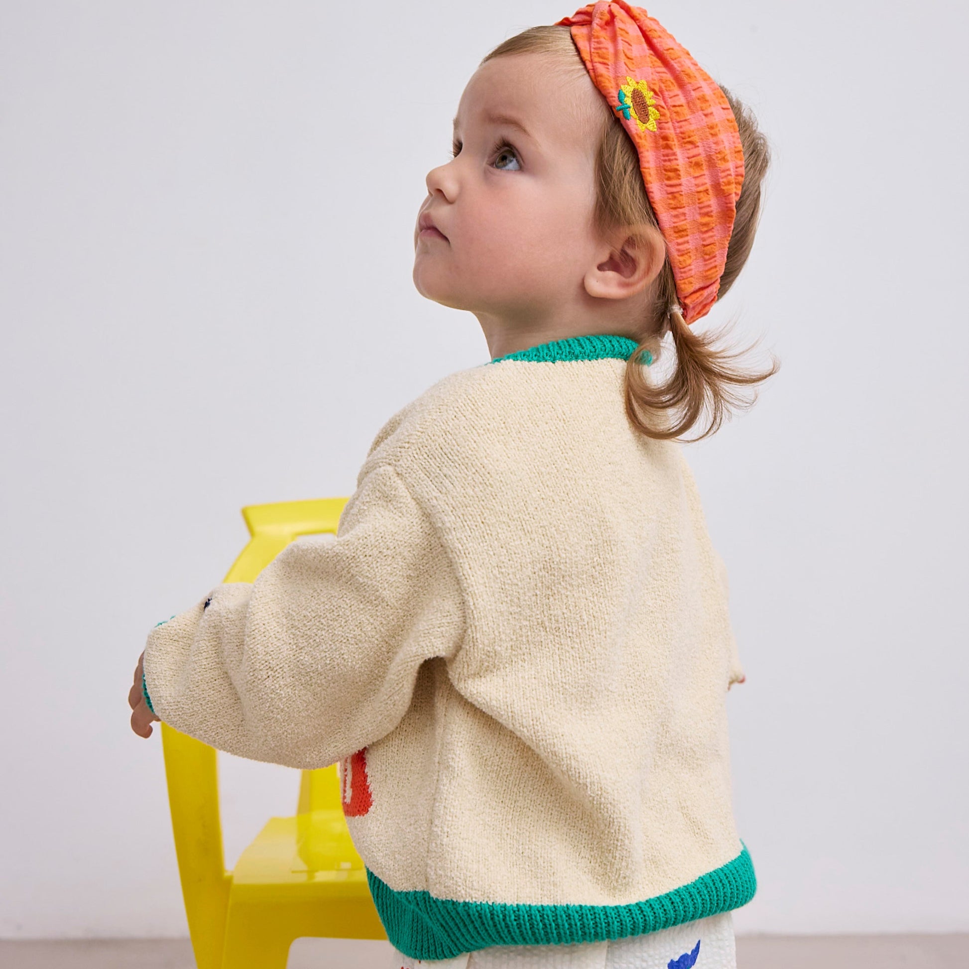 A side profile of the baby wearing the cardigan, highlighting the relaxed fit and soft knit fabric.