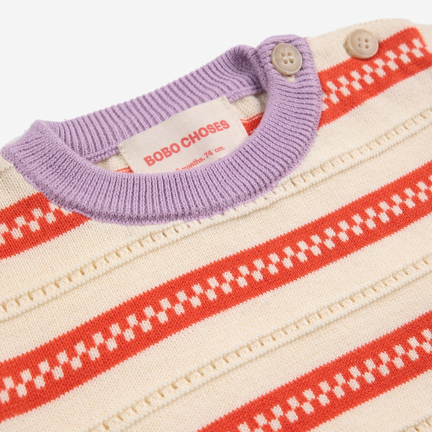 A detailed view of the lilac ribbed collar, wooden-style buttons on the shoulder, and the "Bobo Choses" label stitched inside.