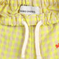 A close-up of the waistband of the baby pants, showing a cream drawstring and the "BOBO CHOSES" brand label sewn inside.