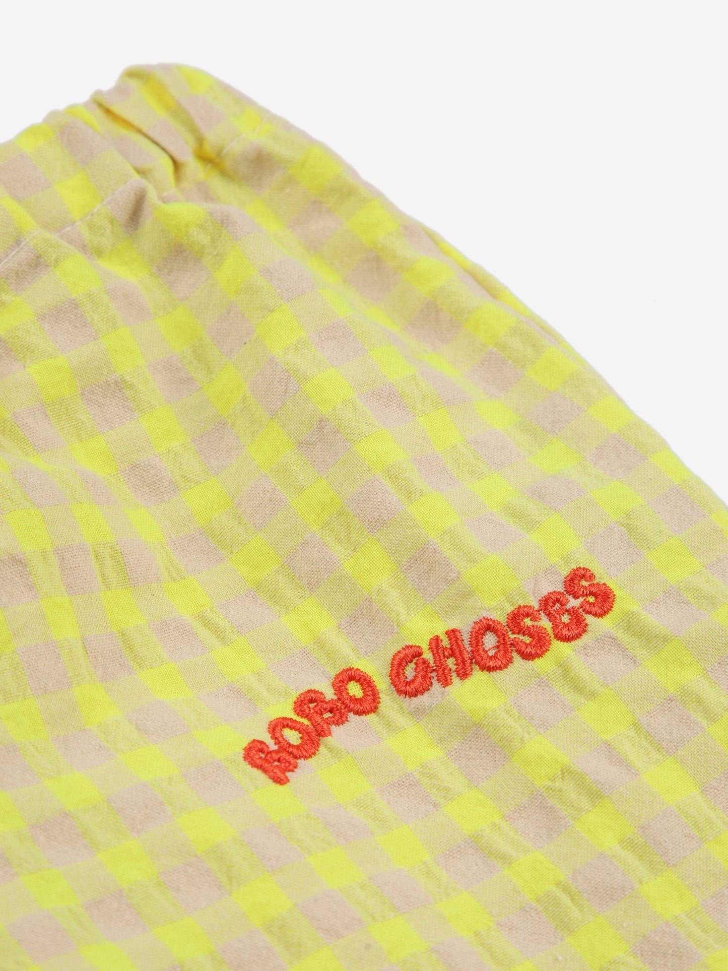 A close-up of the red embroidered "BOBO CHOSES" logo on the gingham fabric.