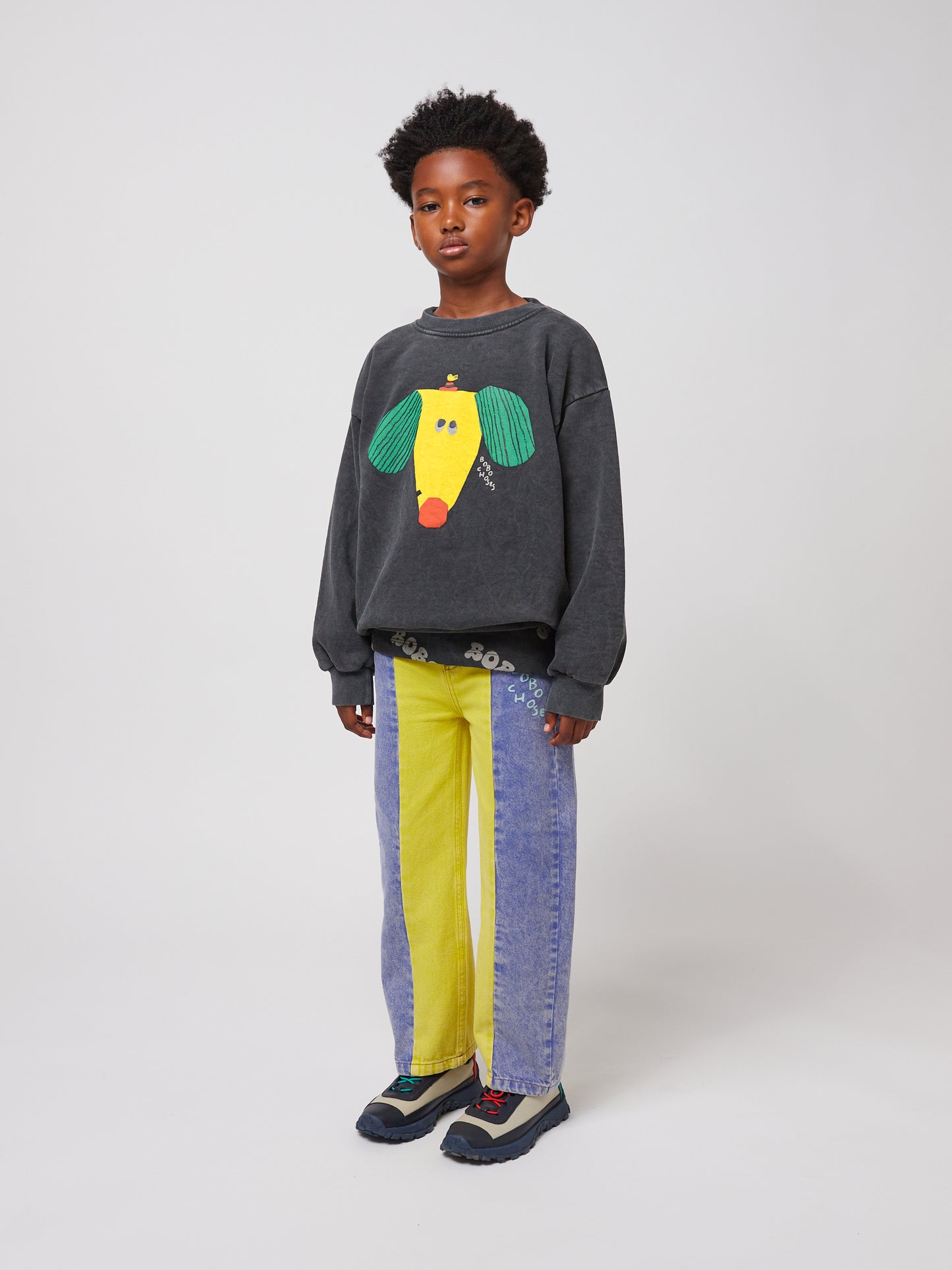 Side-angle shot of the child wearing the sweatshirt and jeans. The relaxed fit of the sweatshirt is visible, along with the two-tone denim pattern.