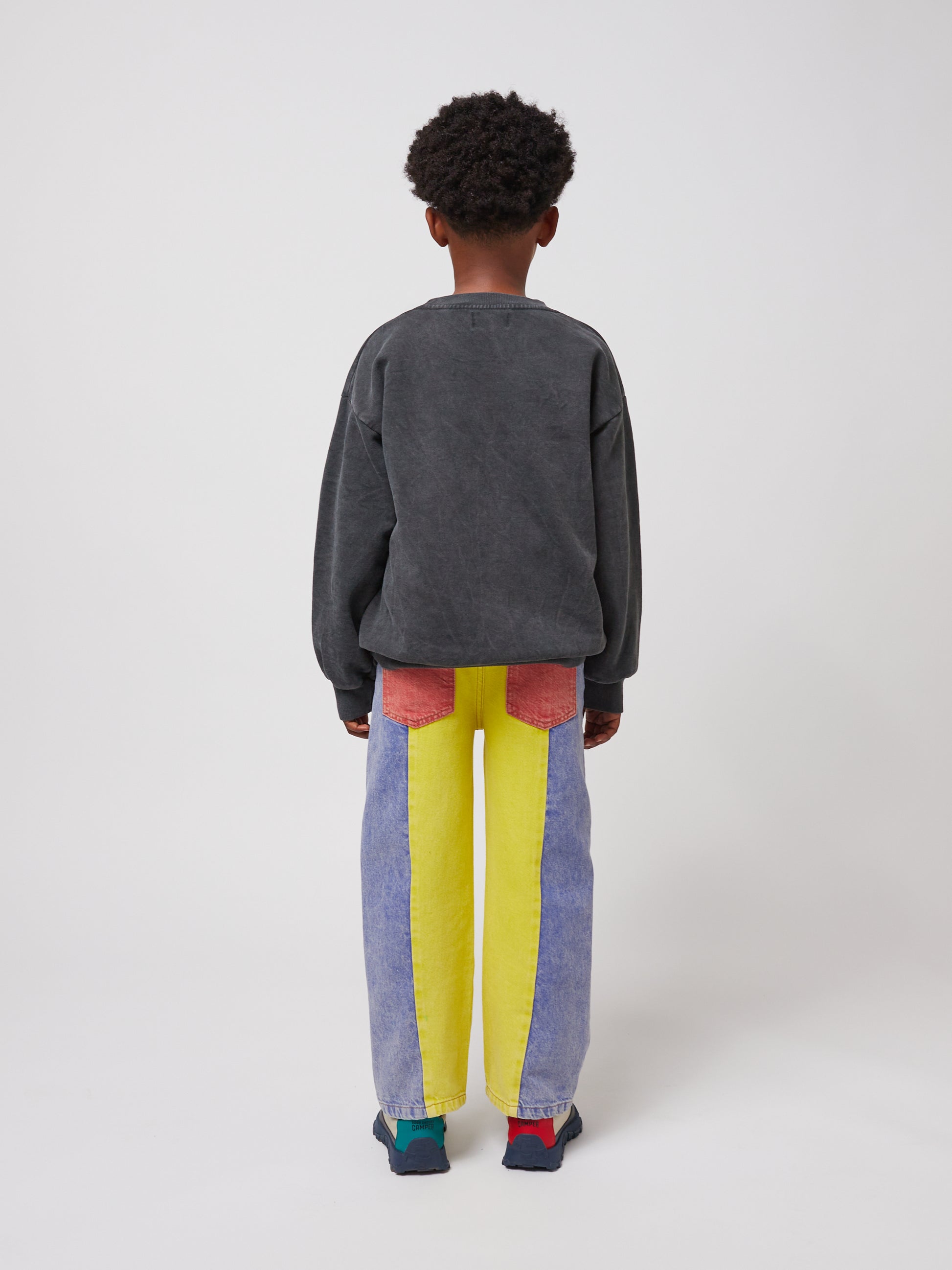 Rear view of the outfit, showing the sweatshirt’s plain dark grey back. The jeans have contrasting back pockets in red and blue.