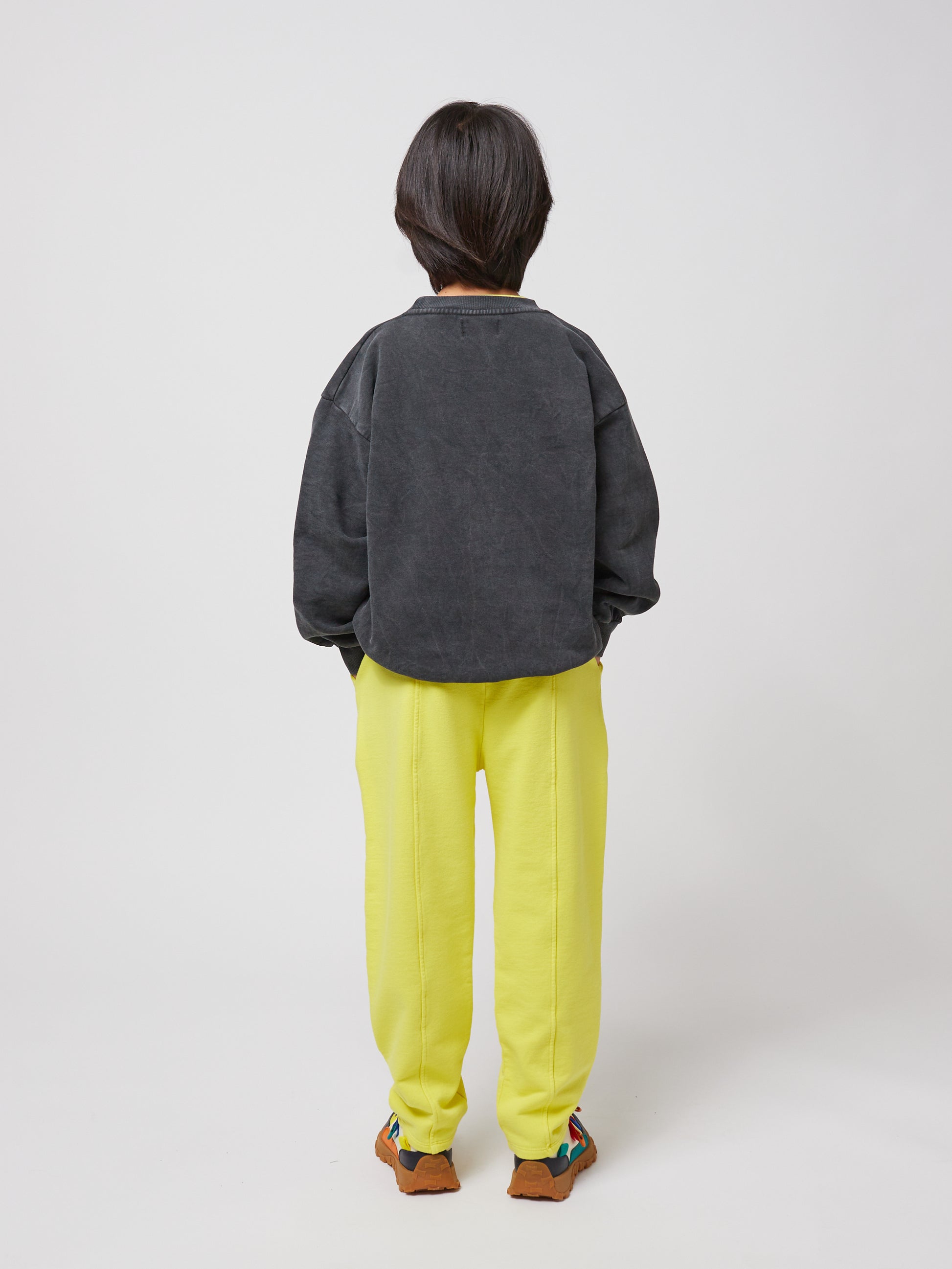 Rear view of the second child’s outfit, showing the sweatshirt’s plain back and the bright yellow sweatpants.