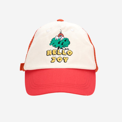 A front view of the Bobo Choses "Hello Joy" mesh cap, showing the embroidered playful tree illustration with a small red character peeking out, along with the curved red brim.