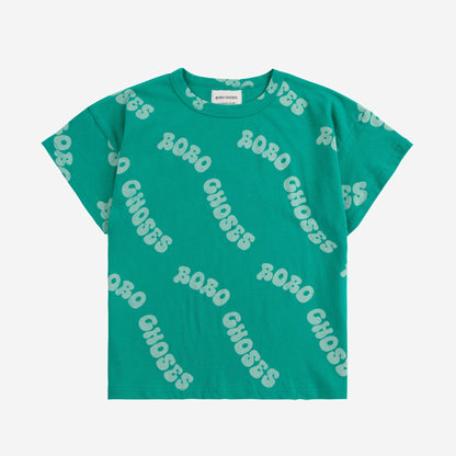 A short-sleeved children's T-shirt in a bold green shade, featuring a repeated "BOBO CHOSES" text print in an irregular, wavy font across the fabric.