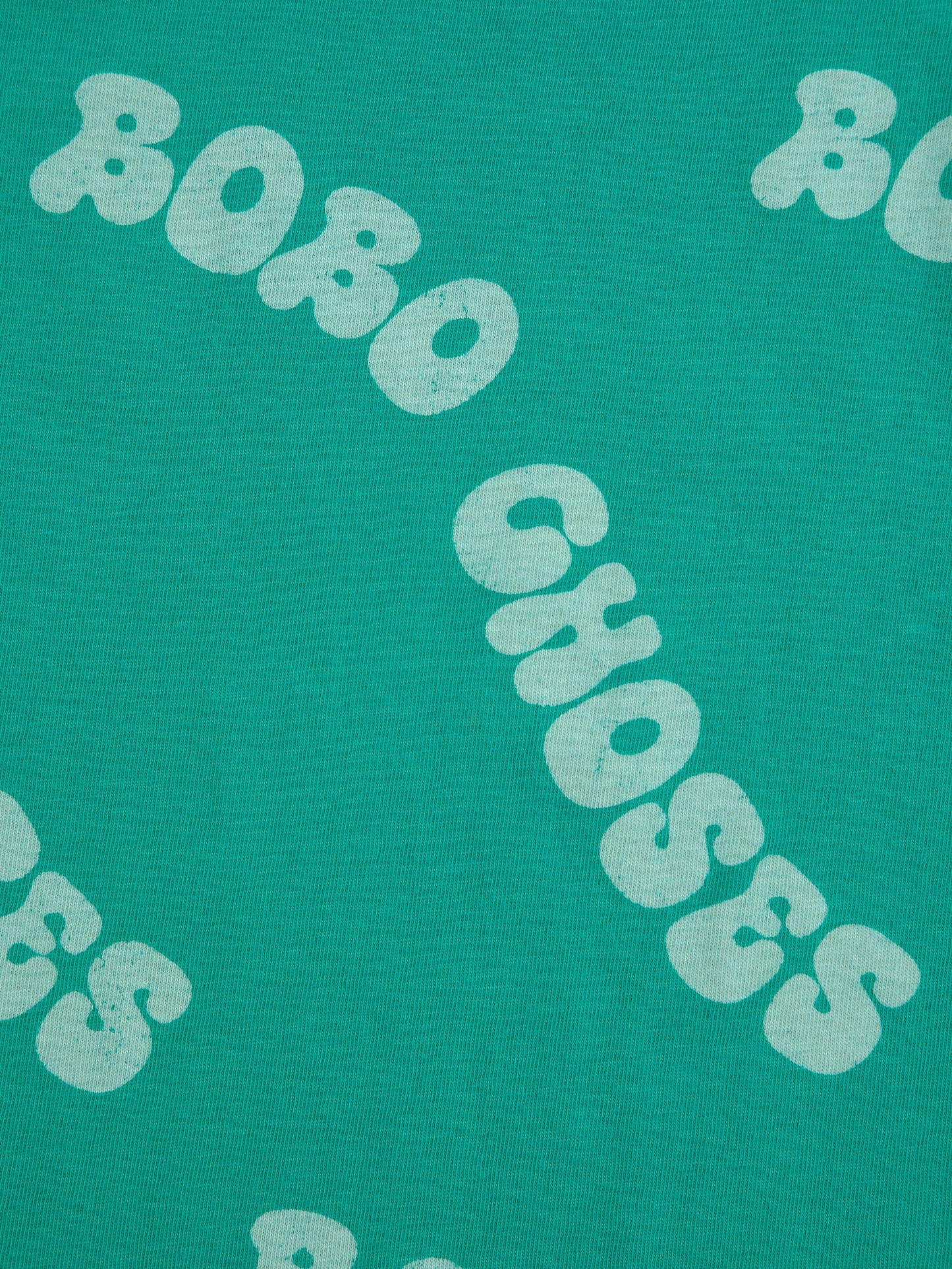 A close-up of the "BOBO CHOSES" text printed across the green fabric in an irregular, wavy font.