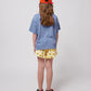 Back view of the girl wearing the blue wavy t-shirt, showing a relaxed oversized fit.