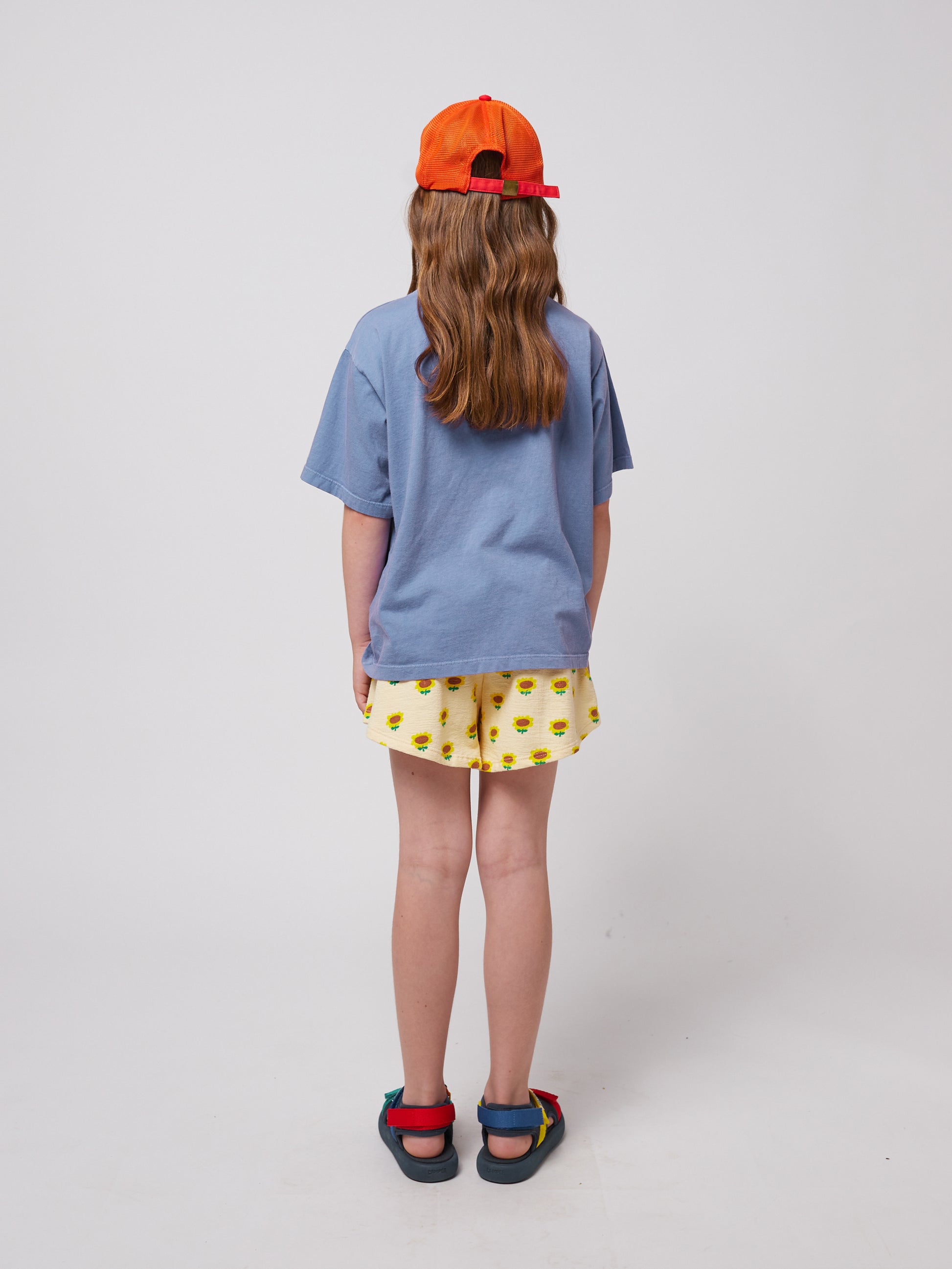 Back view of the girl wearing the blue wavy t-shirt, showing a relaxed oversized fit.