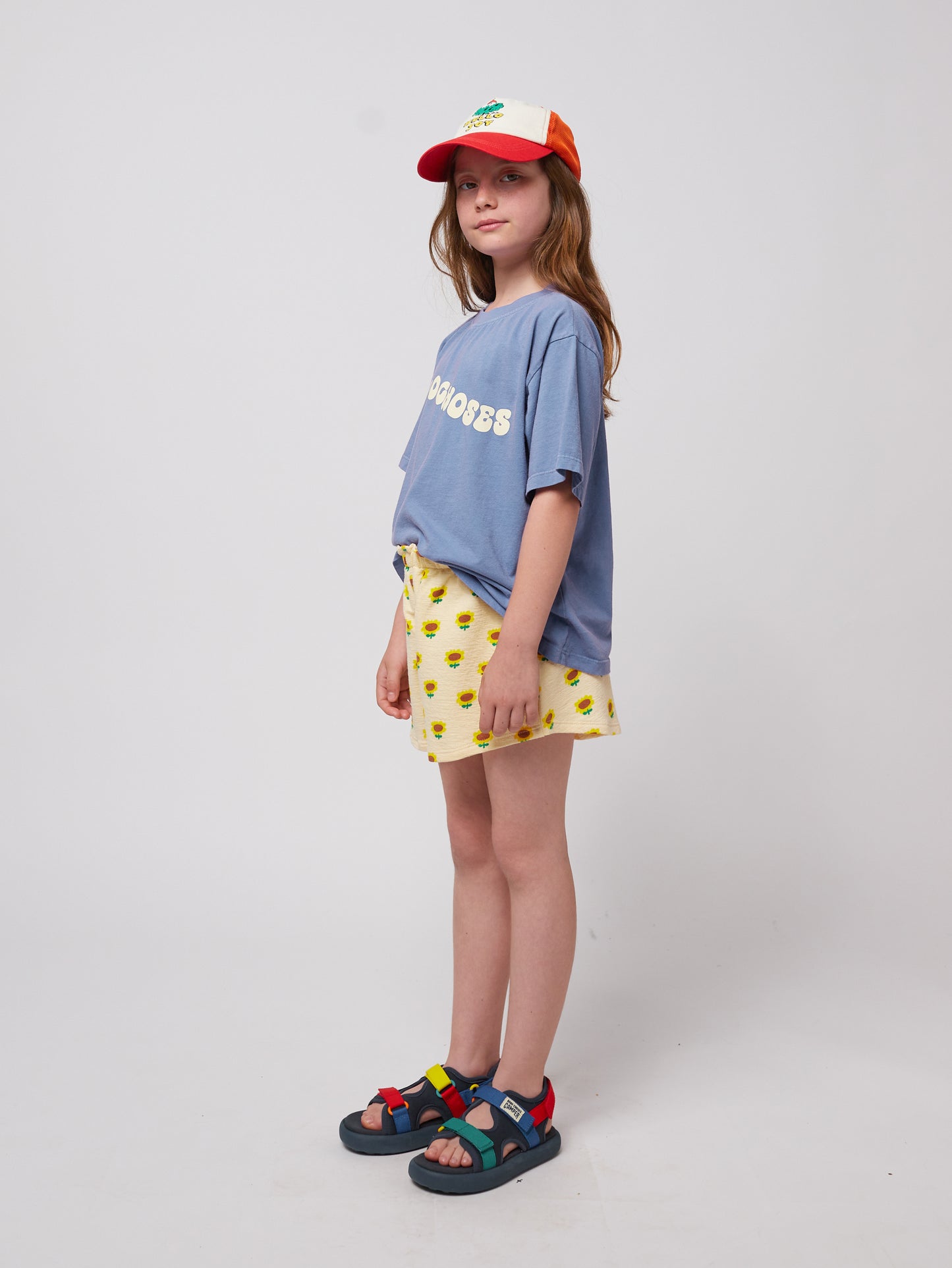 Side view of the girl wearing the blue wavy t-shirt with yellow sunflower shorts.