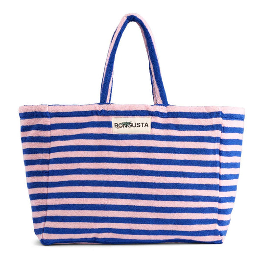 A light pink and dark blue weekend style tote bag with thin red stripes, made of towelling fabric with a long pink and blue striped handle. At the top of the bag it says BONGUSTA in black with green flowers coming off the letters, inside of a cream box. 