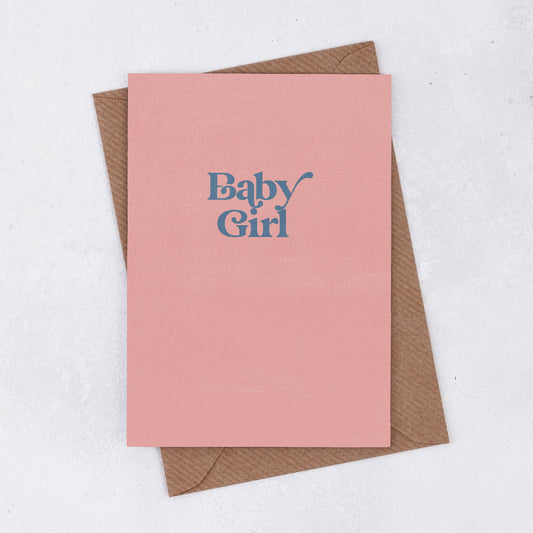 A simple pink greeting card in peachy pink with the words Baby Grirl own a retro font in grey/blue colour. Comes with a brown Kraft envelope