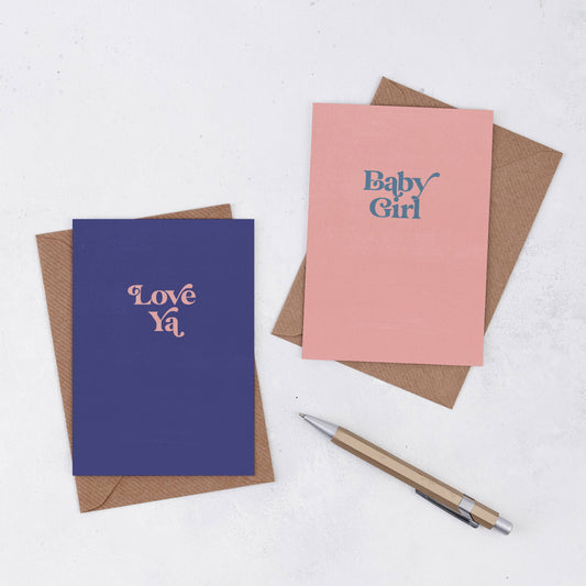 A simple pink greeting card in peachy pink with the words Baby Grirl own a retro font in grey/blue colour. Comes with a brown Kraft envelope. There is also a blue cards with the words Love Ya in pink