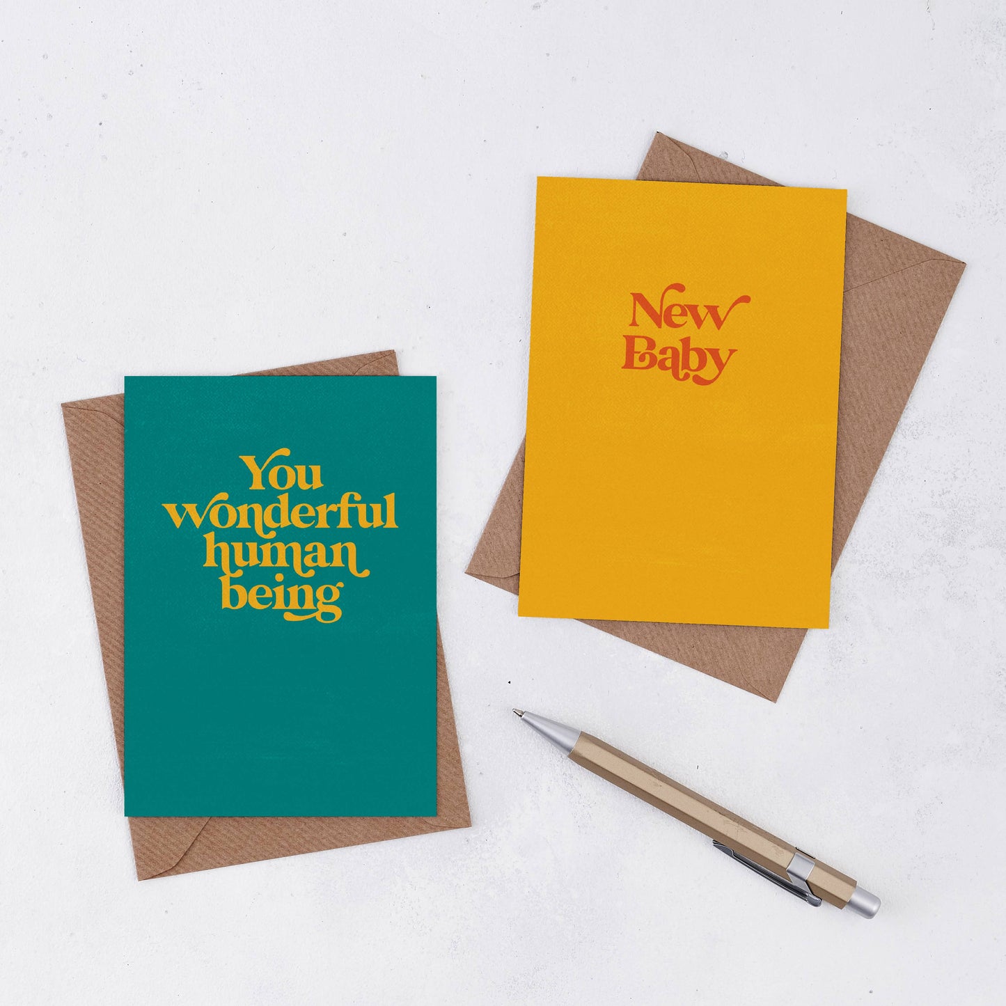 A bright yellow card with the words New Baby in red retro font. Comes with a brown Kraft envelope . A teal card with the words You Wonderful Human Being in yellow.