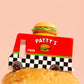Toy truck labeled 'Patty's' with a hamburger on top, on a pink background
