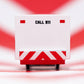 White emergency vehicle with red and white striped panel and 'CALL 911' text on a red and white striped background.