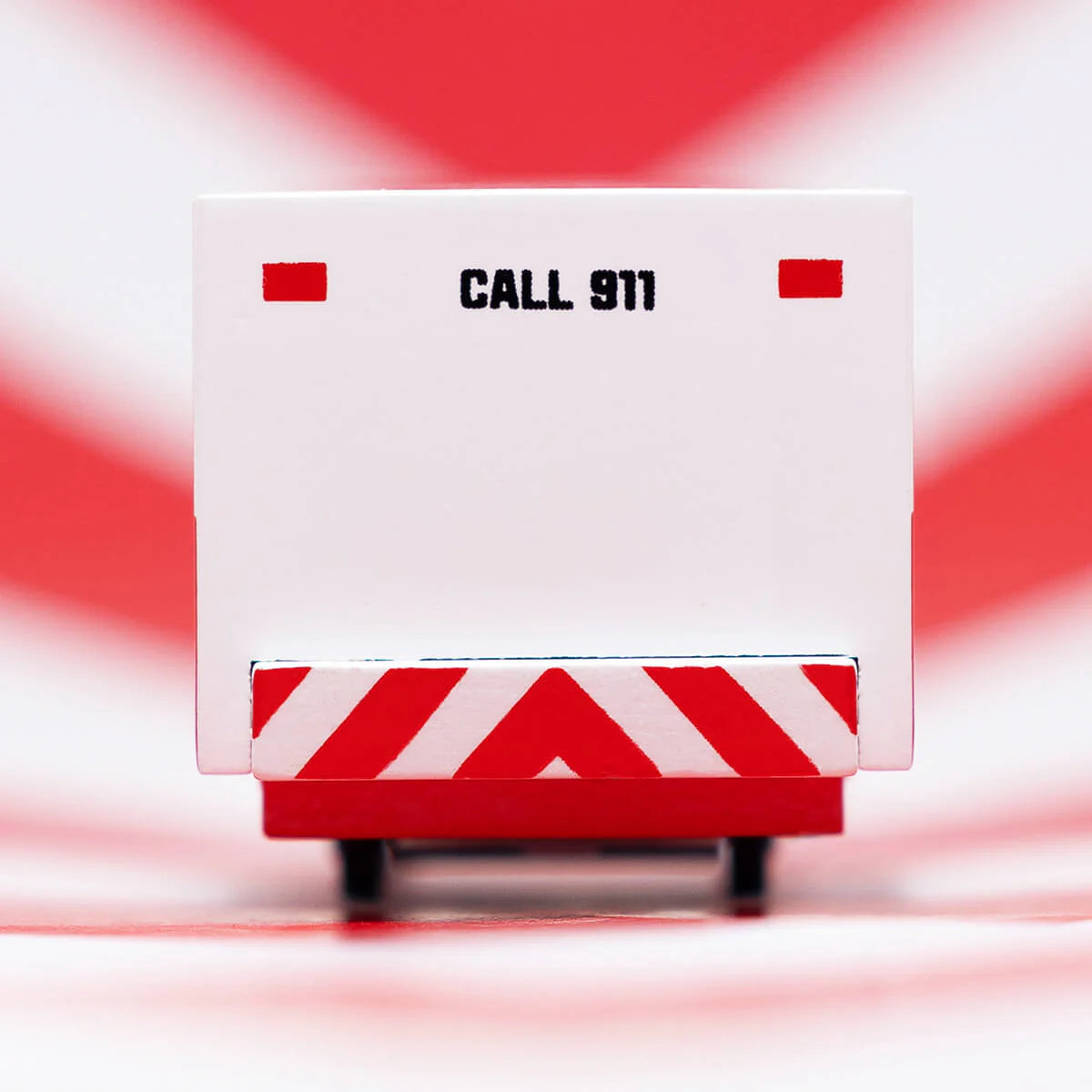 White emergency vehicle with red and white striped panel and 'CALL 911' text on a red and white striped background.