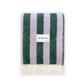 A striped blanket with alternating green and purple stripes, featuring fringes on the short sides and the Maison Deux brand tag visible.